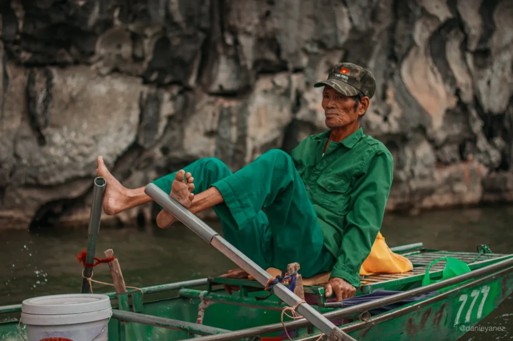 Hombre vietnamita remando con los pies en Tam Coc, Ninh Binh