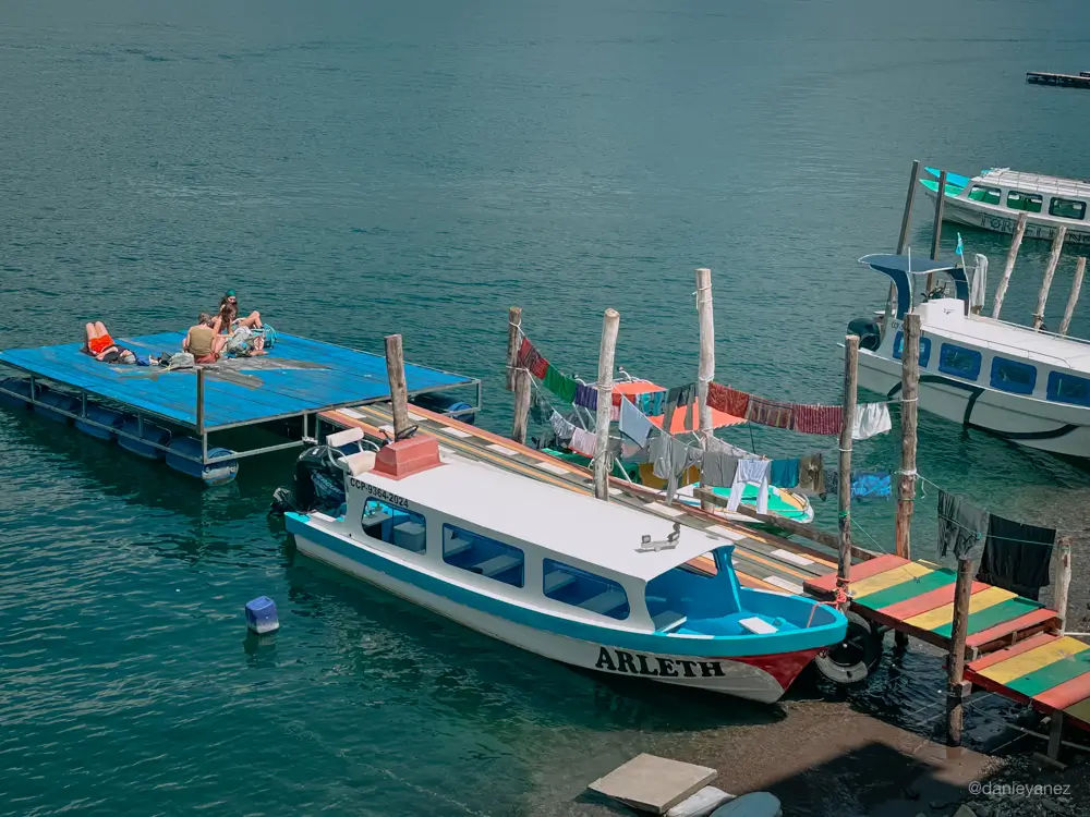 Lanchas estacionadas en San Pedro la Laguna, personas tomando el sol en el muelle
