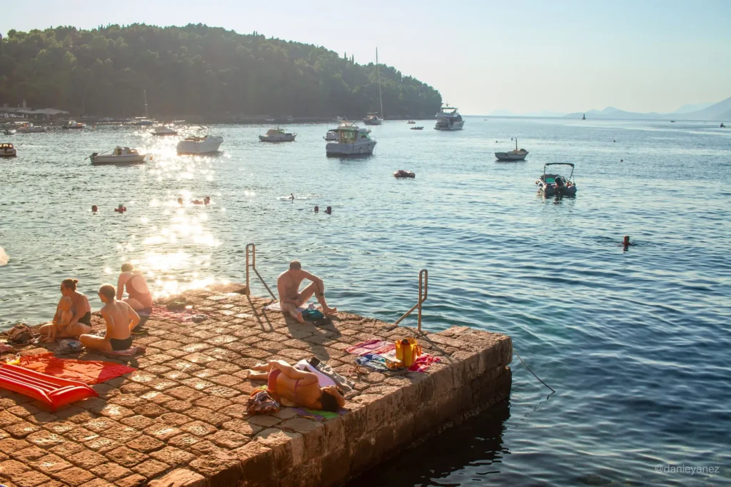 fotoperiodismo, tarde soleada en cavtat Croácia, personas tomando el sol y botes en la distancia